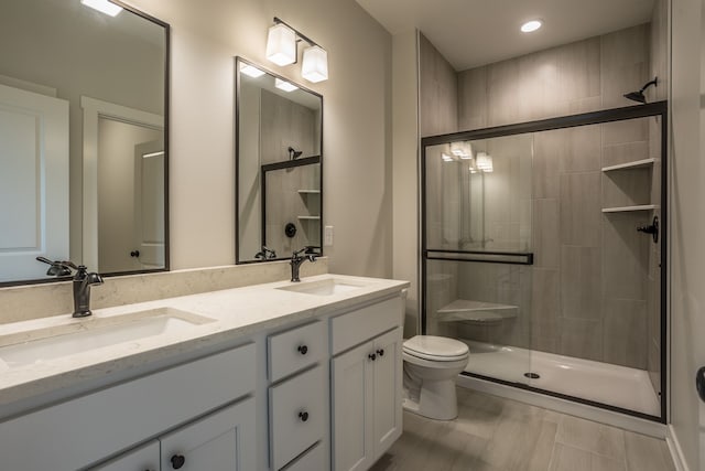 bathroom with vanity, toilet, and a shower with door