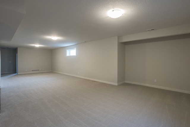 basement featuring a textured ceiling and light colored carpet