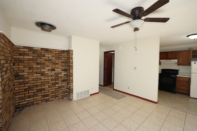 unfurnished living room featuring a textured ceiling, light tile patterned flooring, ceiling fan, and brick wall