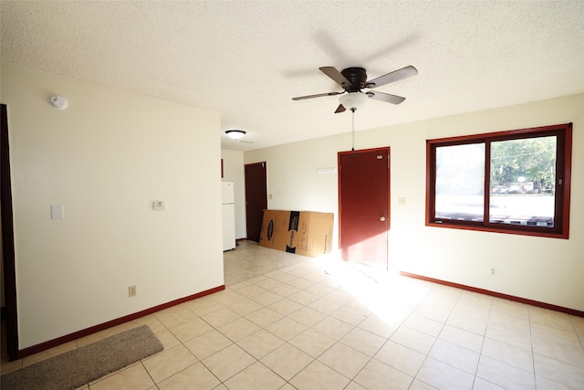 empty room with light tile patterned floors, a textured ceiling, and ceiling fan