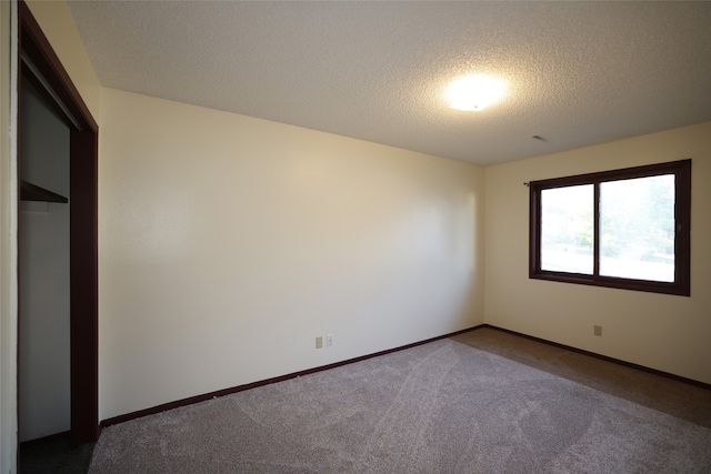 unfurnished bedroom featuring a textured ceiling and dark carpet