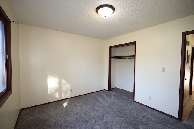 unfurnished bedroom featuring dark carpet, a closet, and a textured ceiling