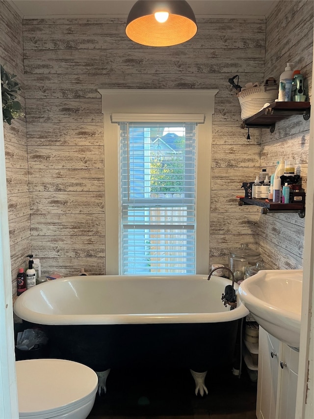 bathroom with vanity, wooden walls, toilet, and a washtub