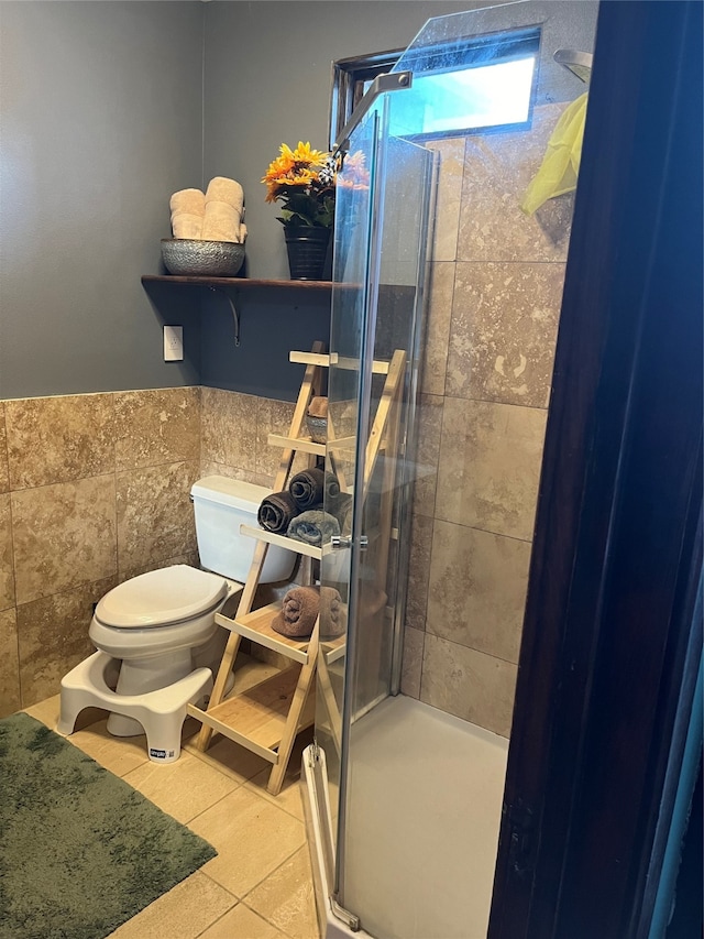 bathroom featuring tile walls, a shower with door, toilet, and tile patterned floors