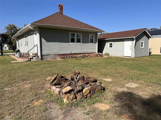 back of house featuring a yard and a fire pit