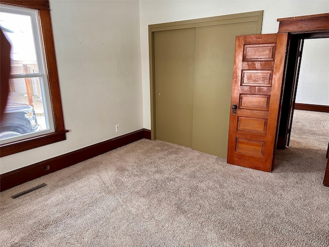 unfurnished bedroom featuring light colored carpet and a closet