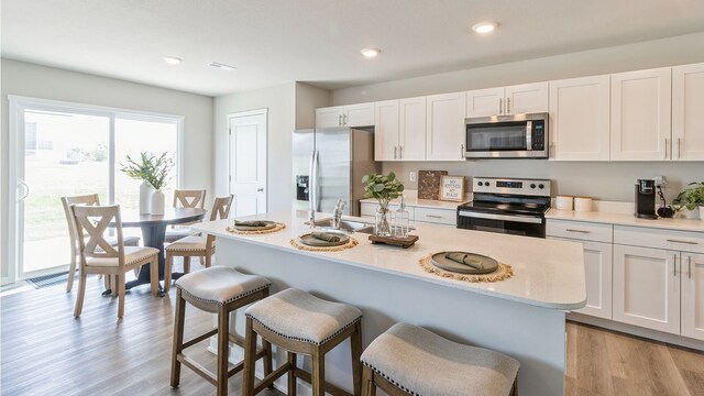 kitchen with white cabinets, stainless steel appliances, and light hardwood / wood-style flooring