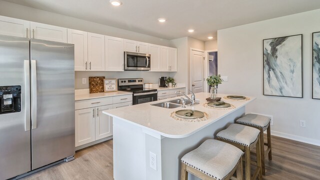 kitchen with light hardwood / wood-style flooring, stainless steel appliances, white cabinetry, and sink