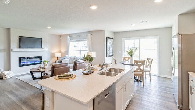 kitchen featuring a wealth of natural light, white cabinetry, a center island with sink, and stainless steel appliances