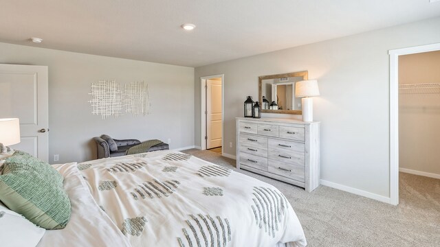 bedroom featuring light colored carpet, a spacious closet, and a closet