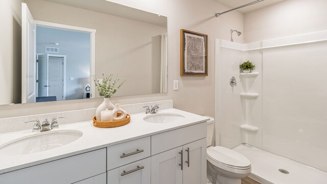 bathroom with vanity, toilet, and a shower