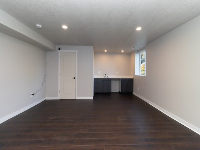 empty room with a textured ceiling, dark hardwood / wood-style floors, and sink