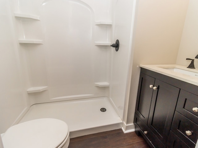 bathroom featuring hardwood / wood-style flooring, a shower, vanity, and toilet