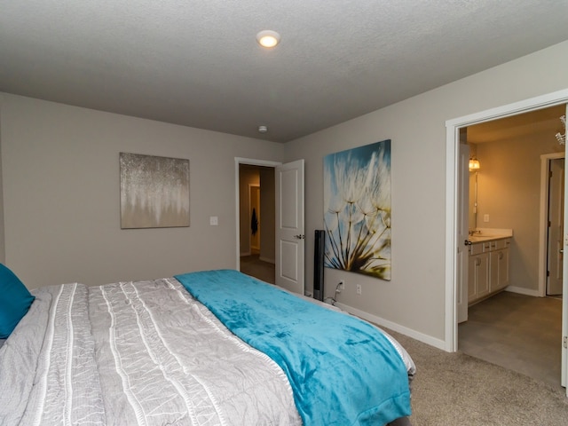 carpeted bedroom featuring a textured ceiling and ensuite bathroom