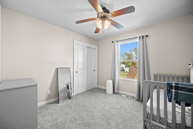 bedroom featuring a textured ceiling, ceiling fan, light colored carpet, and a closet