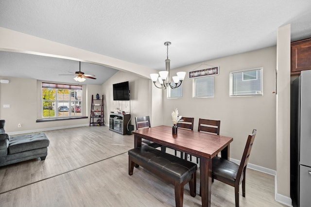 dining room featuring ceiling fan with notable chandelier, a textured ceiling, lofted ceiling, and light wood-type flooring