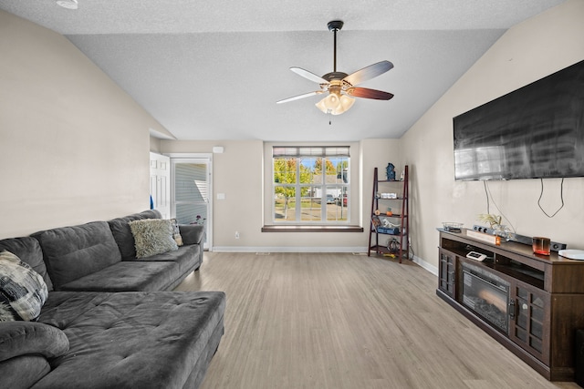 living room with light wood-type flooring, a textured ceiling, vaulted ceiling, and ceiling fan