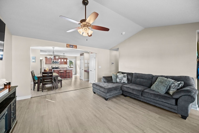 living room featuring ceiling fan with notable chandelier, lofted ceiling, and light wood-type flooring