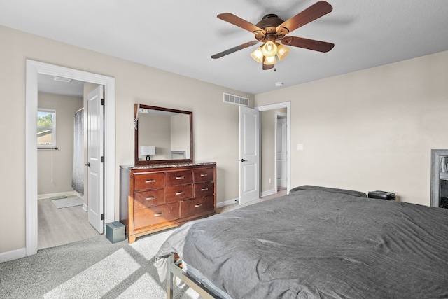 bedroom with ceiling fan, light carpet, and ensuite bathroom