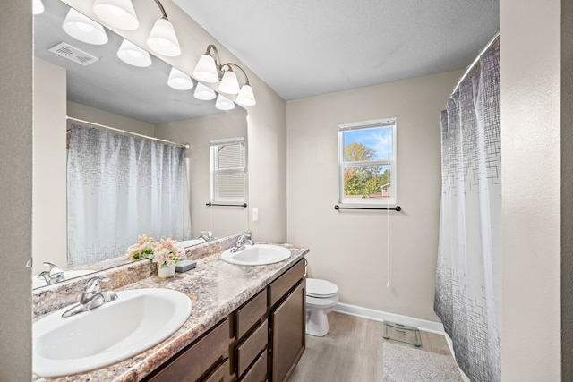 bathroom featuring a textured ceiling, a shower with curtain, hardwood / wood-style floors, vanity, and toilet