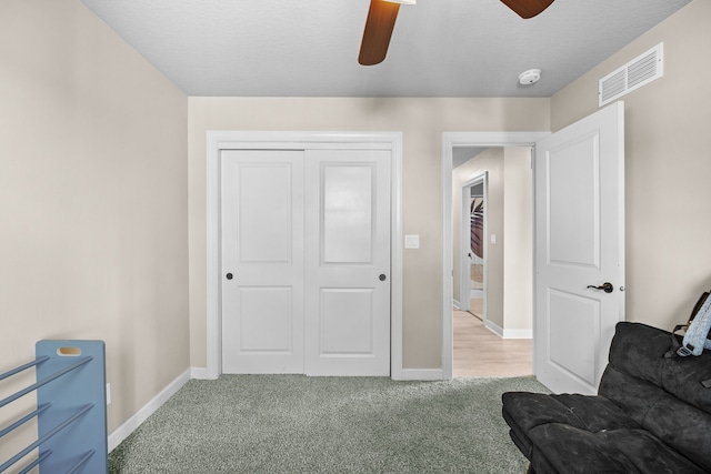 sitting room featuring ceiling fan, light colored carpet, and a textured ceiling