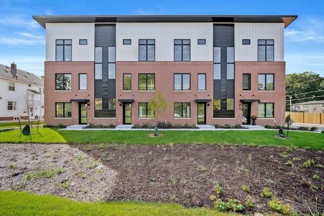 view of front of house featuring a front lawn, board and batten siding, and brick siding