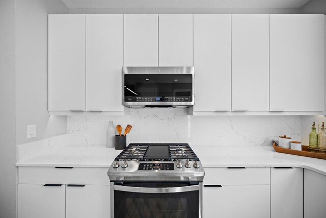 kitchen with light stone counters, appliances with stainless steel finishes, backsplash, and white cabinetry