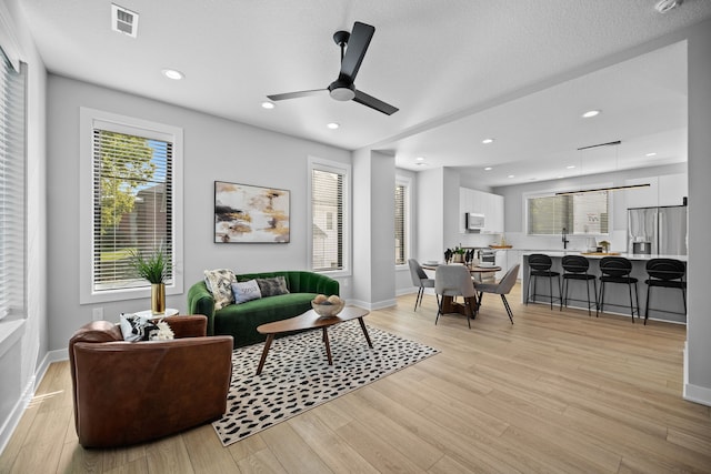 living room featuring recessed lighting, baseboards, visible vents, and light wood finished floors