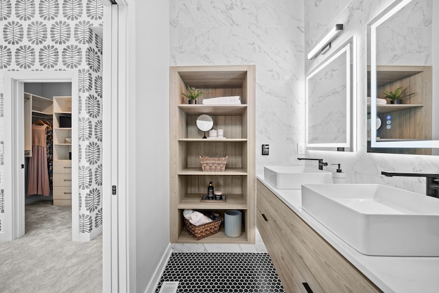 bathroom with built in shelves, a sink, a spacious closet, and double vanity