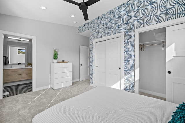 bedroom featuring multiple closets, recessed lighting, ensuite bathroom, light carpet, and baseboards