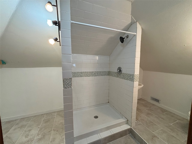 bathroom with tiled shower and lofted ceiling