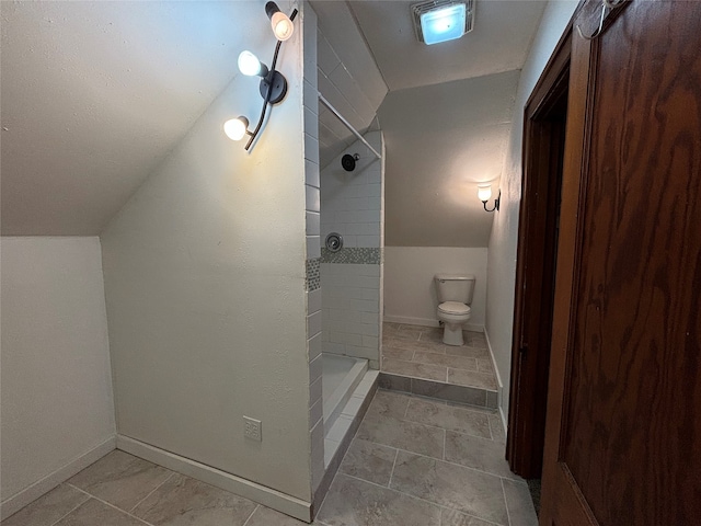 bathroom featuring tiled shower, vaulted ceiling, and toilet