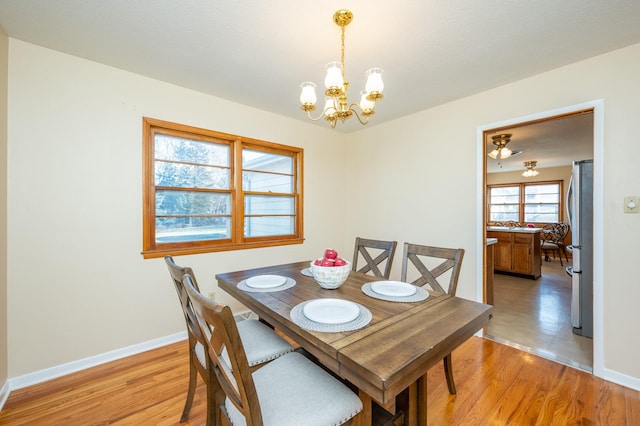 dining space featuring light wood-type flooring and an inviting chandelier