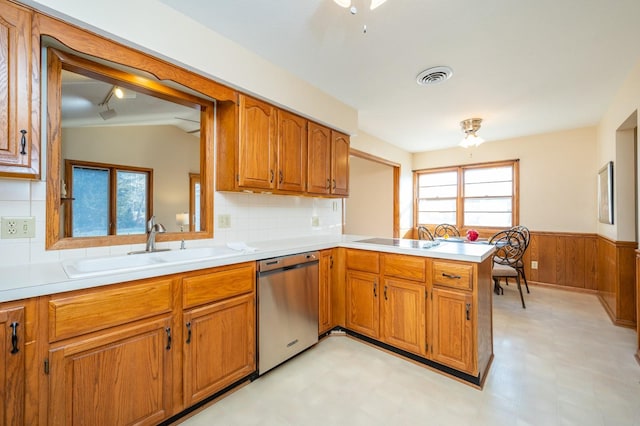 kitchen with wood walls, sink, stainless steel dishwasher, decorative backsplash, and kitchen peninsula