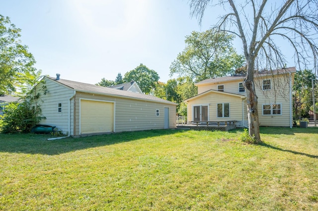 rear view of property featuring a lawn, a garage, and an outdoor structure