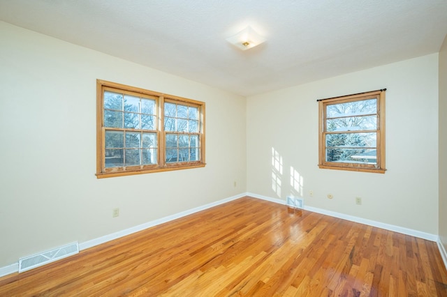 empty room with hardwood / wood-style flooring and a healthy amount of sunlight