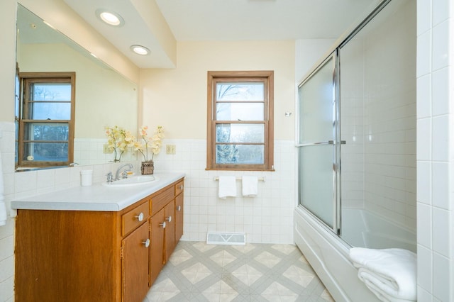 bathroom featuring vanity, enclosed tub / shower combo, and tile walls