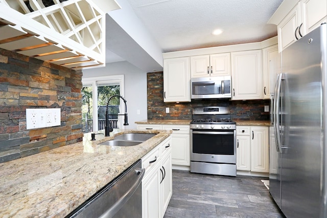 kitchen featuring tasteful backsplash, light stone countertops, sink, white cabinetry, and stainless steel appliances