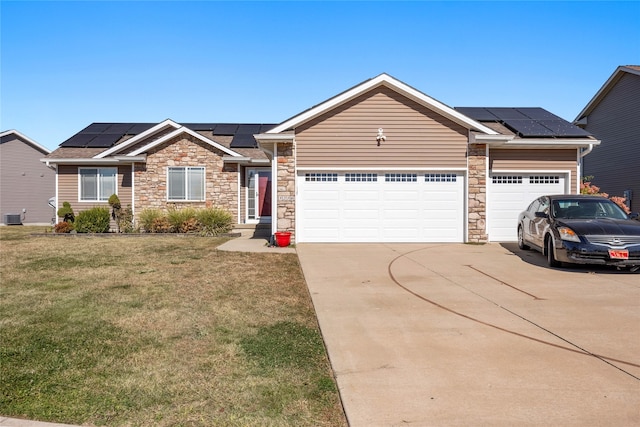 view of front of home with cooling unit, a front yard, solar panels, and a garage