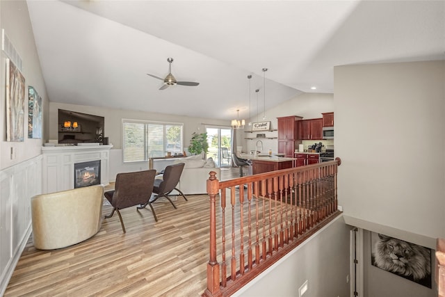 interior space featuring ceiling fan with notable chandelier, vaulted ceiling, and hardwood / wood-style flooring