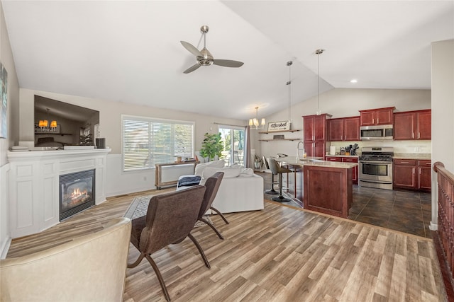 living room featuring ceiling fan with notable chandelier, lofted ceiling, dark wood-type flooring, and sink