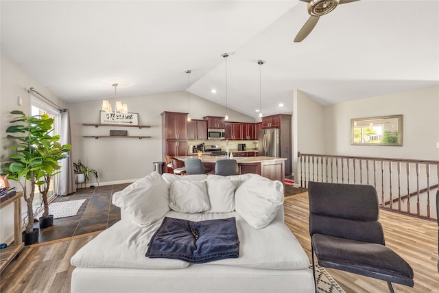 living room featuring ceiling fan with notable chandelier, lofted ceiling, and dark wood-type flooring