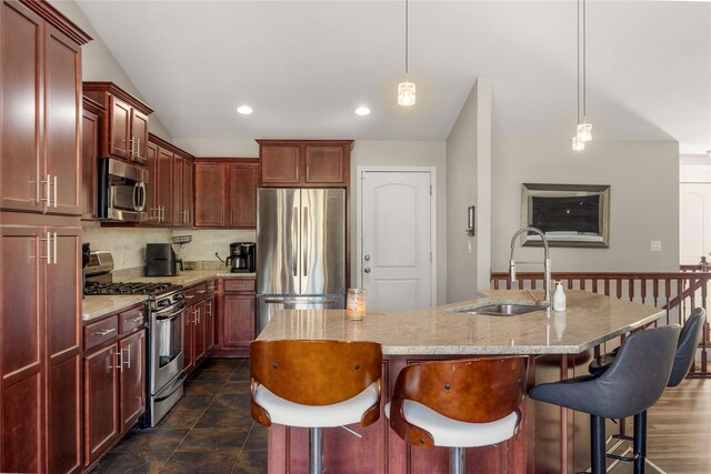 kitchen with sink, decorative light fixtures, a center island with sink, stainless steel appliances, and a breakfast bar