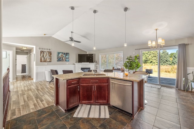 kitchen featuring sink, stainless steel dishwasher, a kitchen island with sink, light stone countertops, and vaulted ceiling