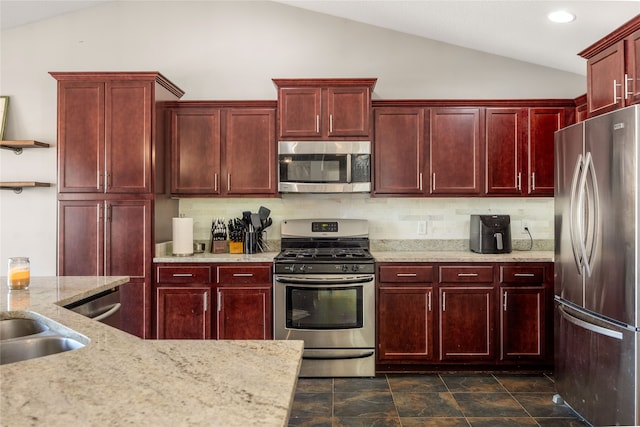 kitchen with light stone counters, appliances with stainless steel finishes, backsplash, and vaulted ceiling