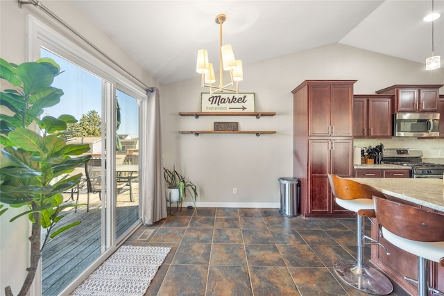 kitchen with stainless steel appliances, vaulted ceiling, light stone counters, and decorative light fixtures