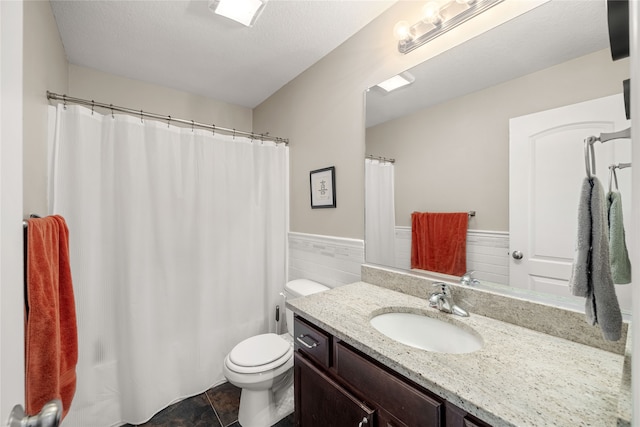 bathroom with vanity, a textured ceiling, tile patterned floors, tile walls, and toilet