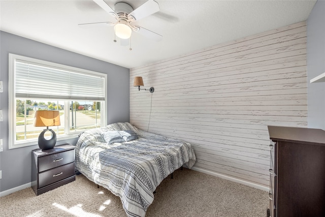 bedroom with ceiling fan, light colored carpet, and wooden walls