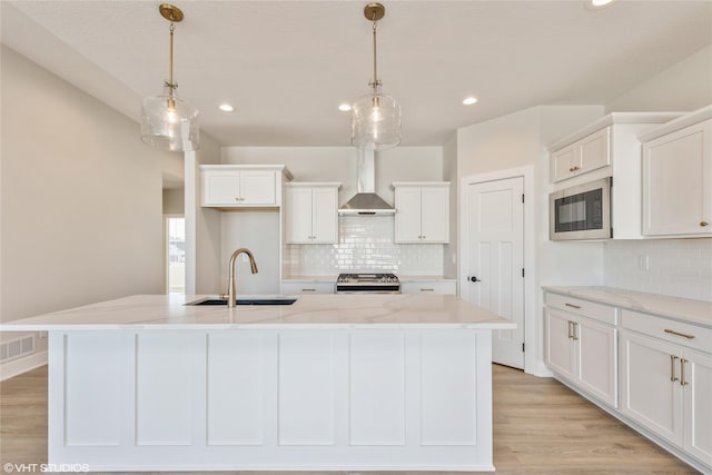 kitchen with wall chimney range hood, a kitchen island with sink, and stove