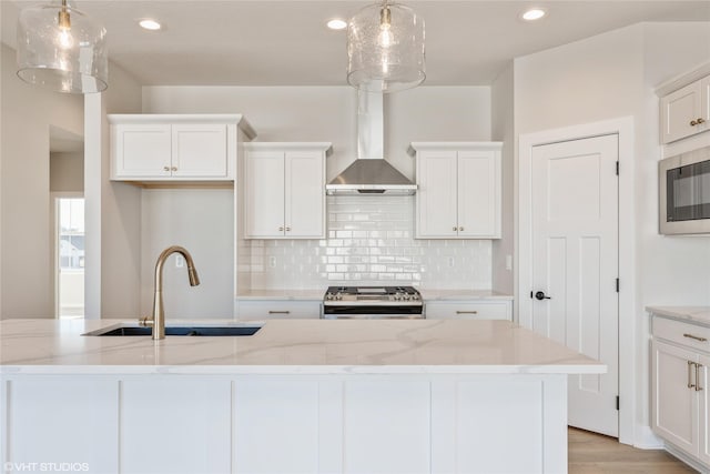 kitchen with hanging light fixtures, appliances with stainless steel finishes, sink, and wall chimney exhaust hood